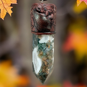 Whimsical baby pixie sleeping in leaves on top of a Moss Agate point, made in a pendant on an adjustable cord made with polymer clay crafted by mouth @ Artbymouth.nz