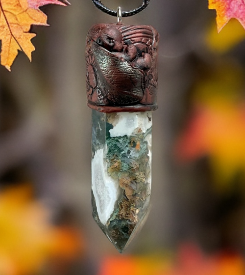 Whimsical baby pixie sleeping in leaves on top of a Moss Agate point, made in a pendant on an adjustable cord made with polymer clay crafted by mouth @ Artbymouth.nz